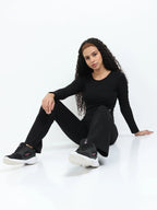 Model in black long sleeve crop top and leggings performing a kneeling side stretch