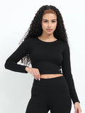 Yellowcrop black long sleeve crop top, front view on model with hand on hip