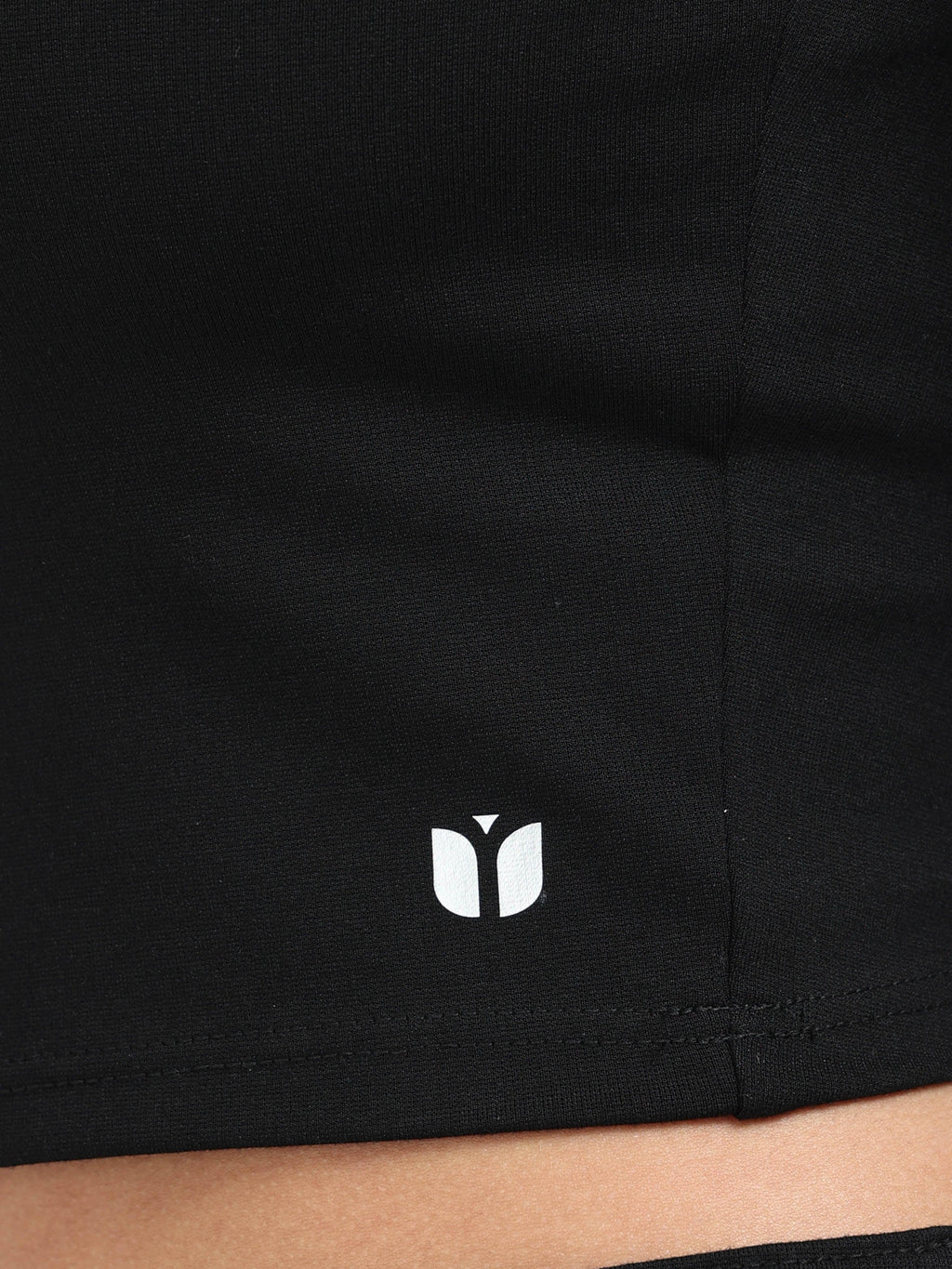 Close-up of Yellowcrop logo emblem on black long sleeve crop top