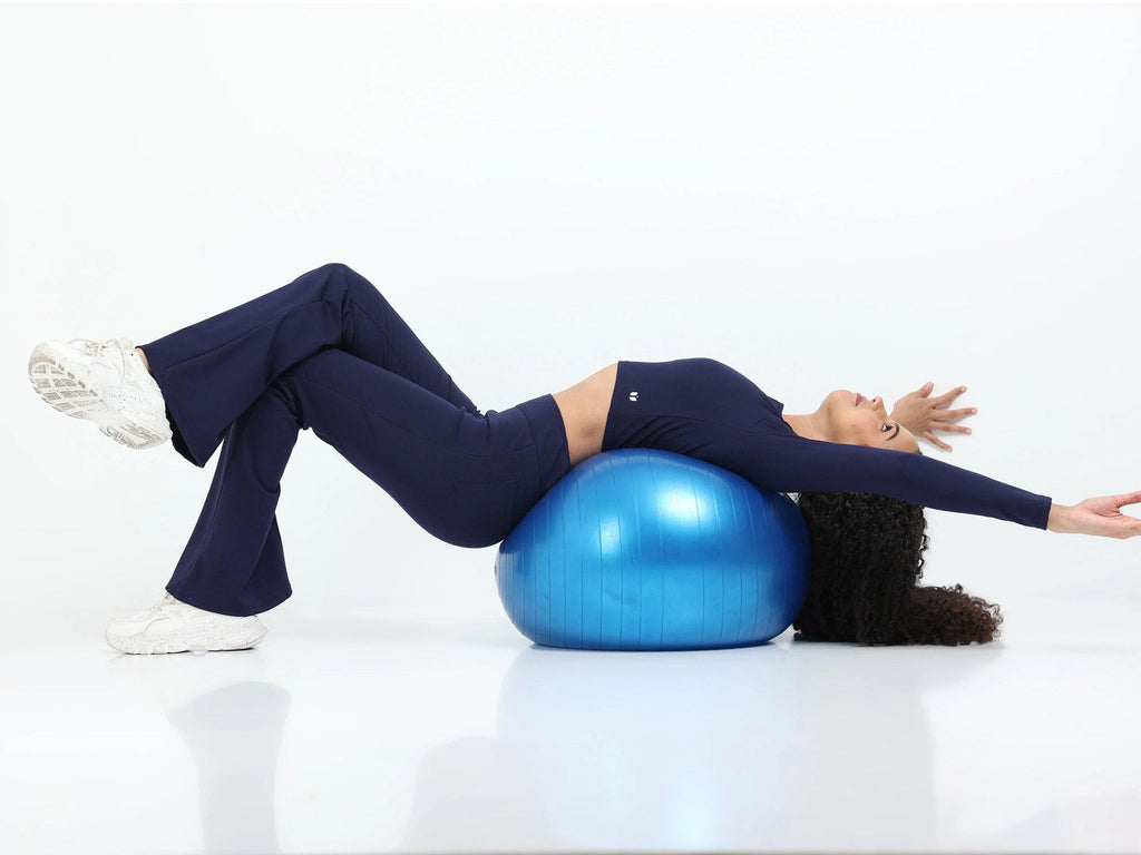 Model in navy long sleeve crop top and leggings performing a kneeling side stretch